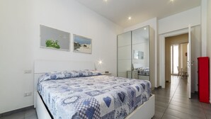 A bedroom with a bed, a large mirror, and a door leading to another room.