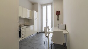 A modern kitchen with white cabinets, a dining table with chairs, and a clock on the wall.