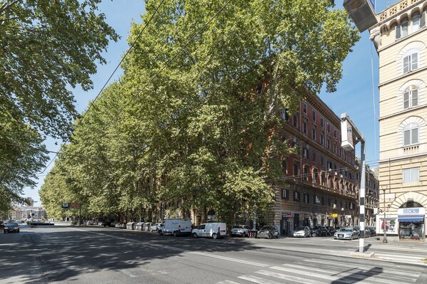 A street lined with trees and buildings, including a row of parked cars and a few pedestrians. - Porta Pia & Villa Torlonia Apartment with Balcony (Rome)