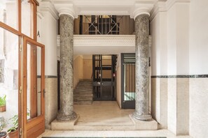 A grand entrance with marble columns, a staircase, and a security gate. - Porta Pia & Villa Torlonia Apartment with Balcony (Rome)