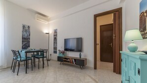 A modern living room with a dining area, a flat-screen TV, and a teal cabinet. - San Giovanni Apartment with Balcony (Rome)
