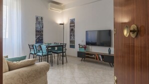 A modern living room with a dining area, a flat-screen TV, and artwork on the walls. - San Giovanni Apartment with Balcony (Rome)