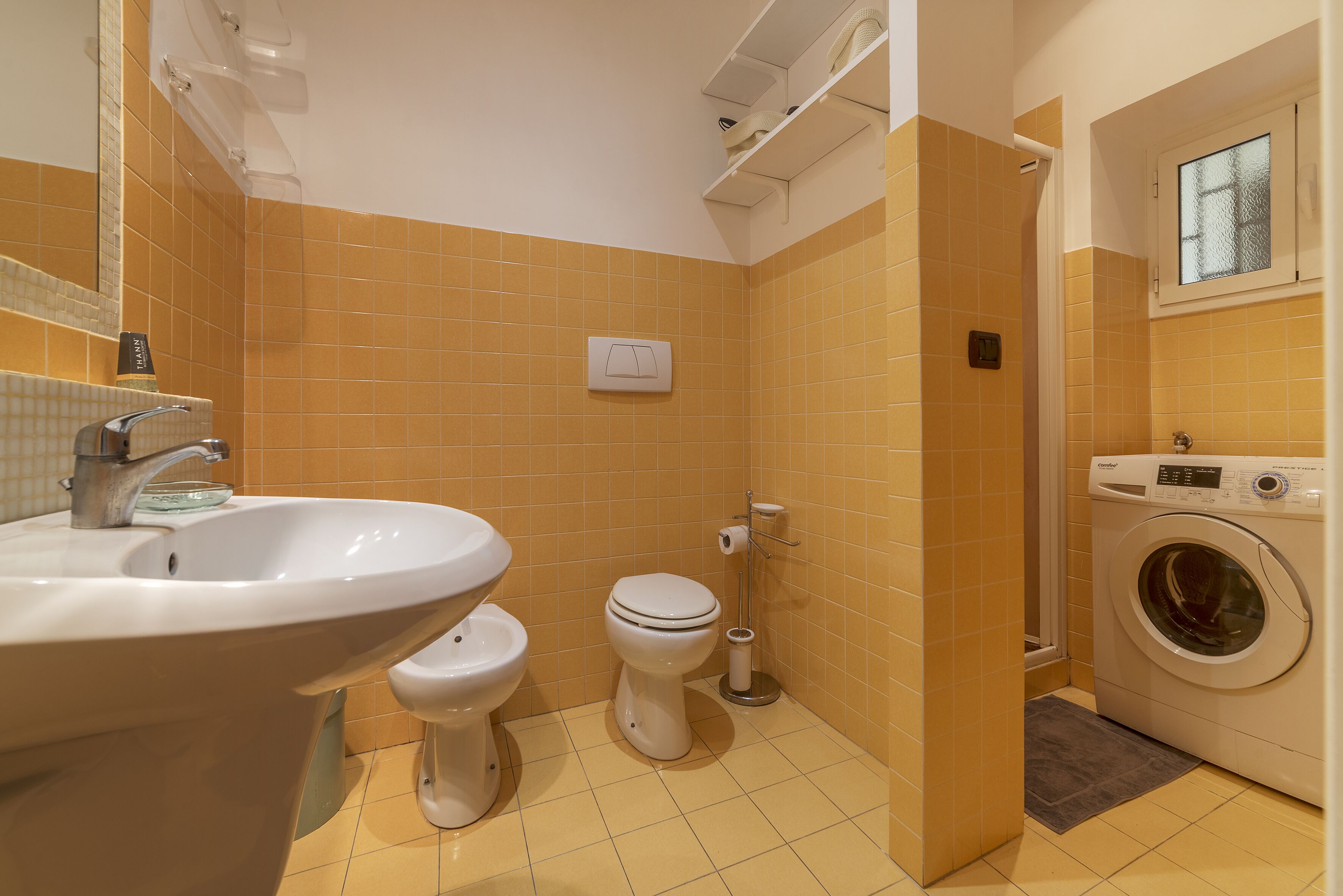 A bathroom with a sink, toilet, and washing machine.