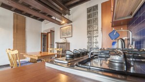 A kitchen with a wooden table and chairs, a stove, and a tiled backsplash.