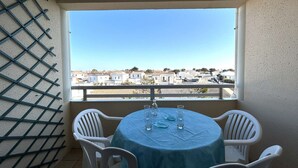 Uma varanda com mesa e cadeiras, vista para uma área residencial.