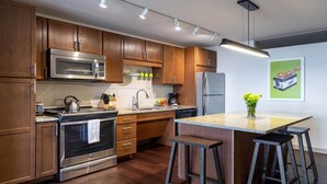 Una cucina moderna con mobili in legno, elettrodomestici in acciaio inossidabile e un'isola centrale con sgabelli da bar.