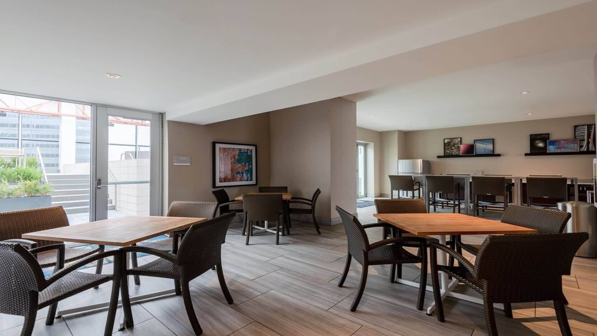 A modern hotel room with a dining area, a kitchen, and a balcony with a view of the city.
