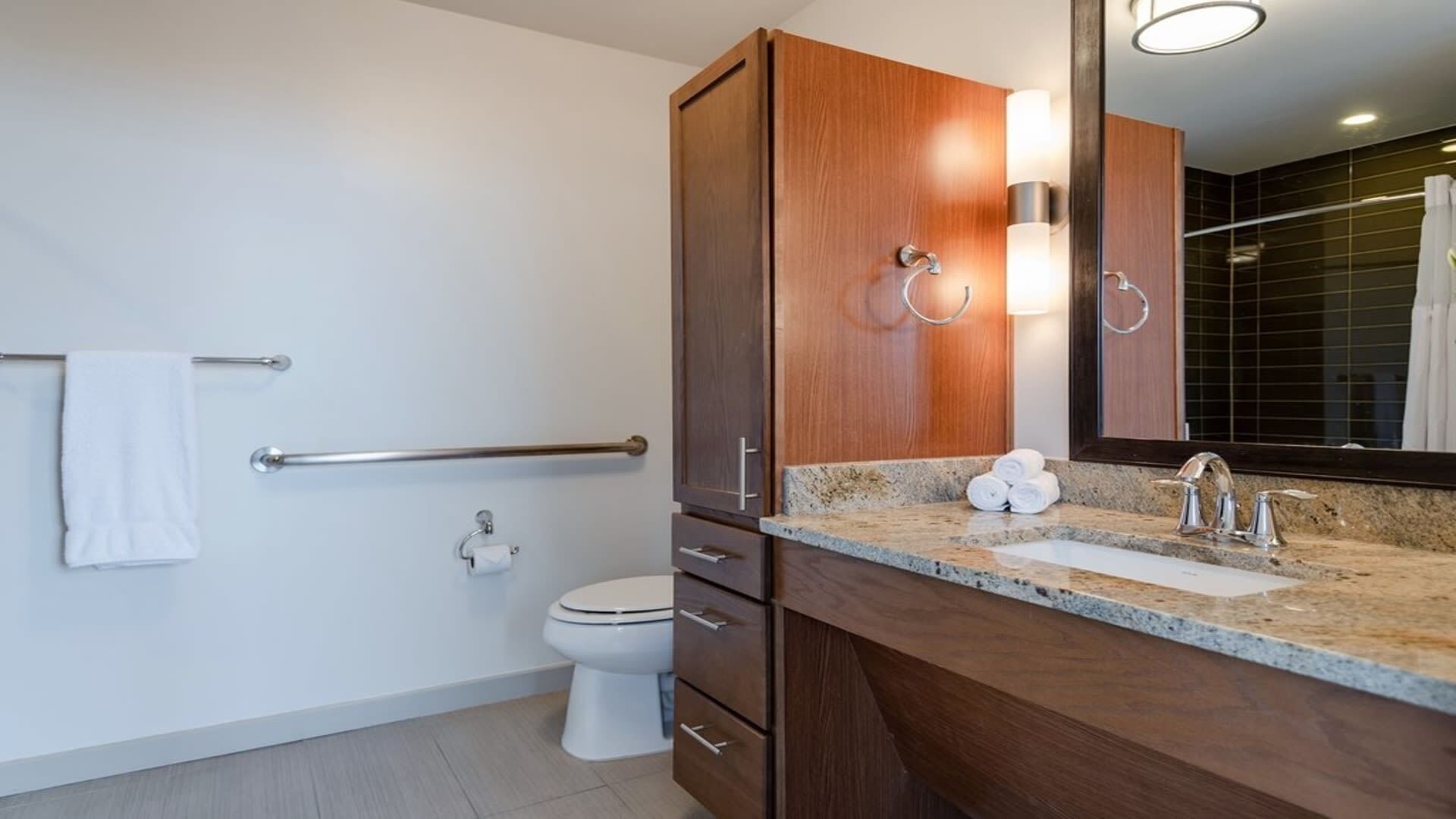 A modern bathroom with a toilet, a sink with a mirror, and a towel rack.