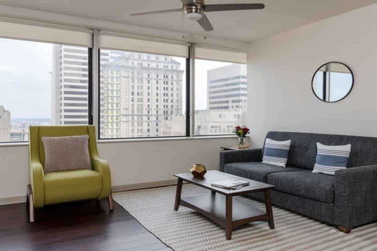 A modern living room with a green armchair, grey sofa, and a coffee table.