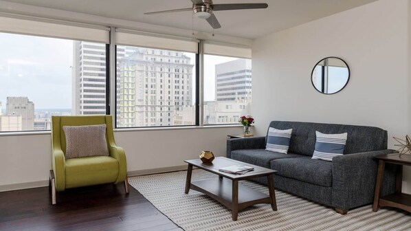 A modern living room with a green armchair, grey sofa, and a coffee table.