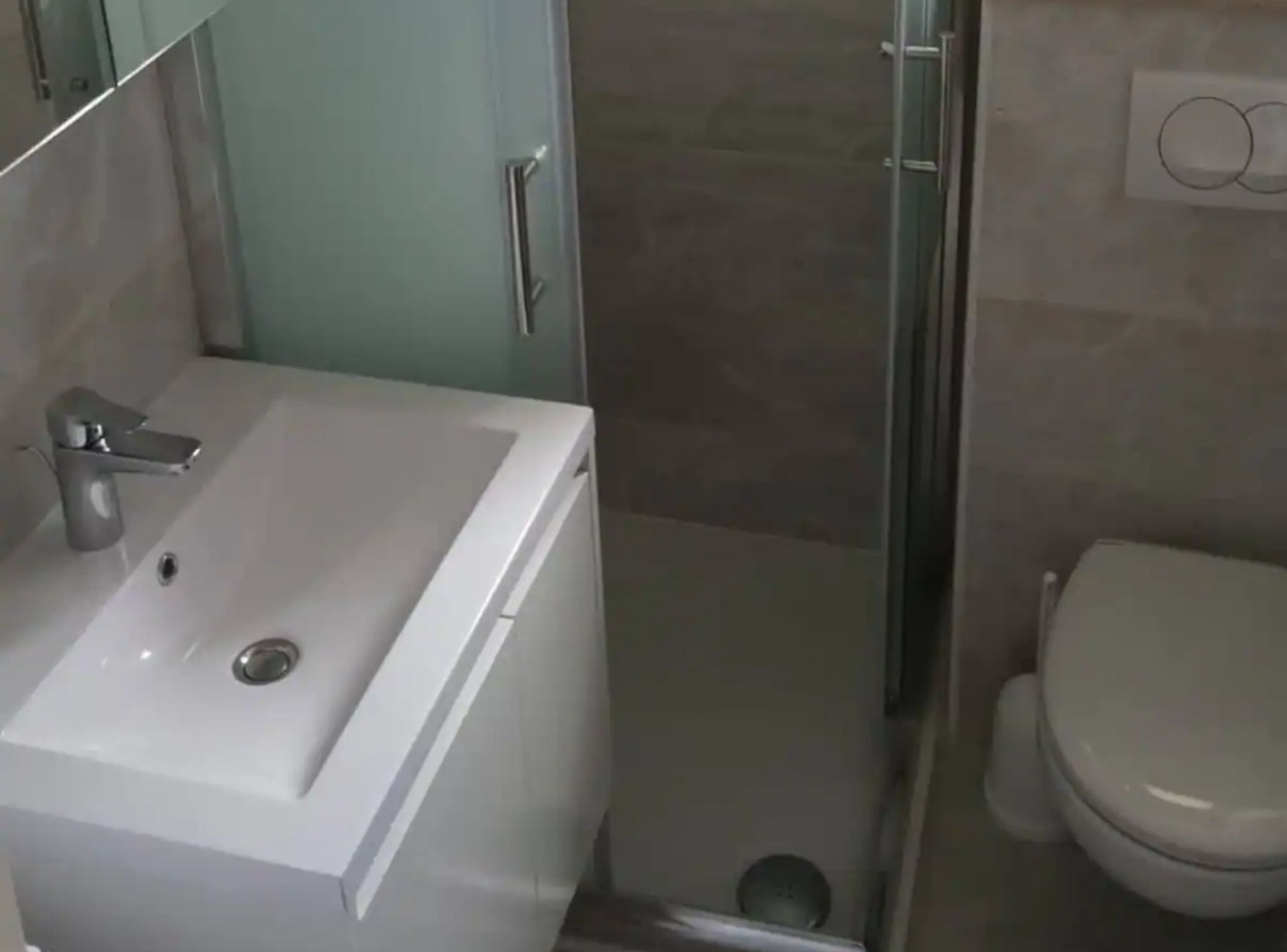 Ein Badezimmer mit einem weißen Waschbecken, einer Toilette und einer Duschkabine aus Glas.