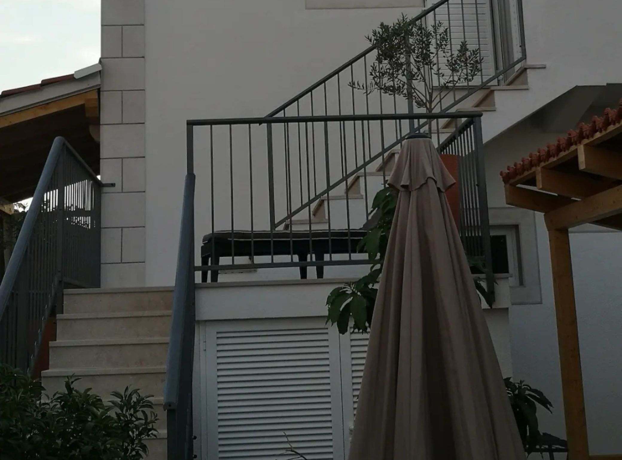 A residential building with a staircase, a balcony, and a covered outdoor area.
