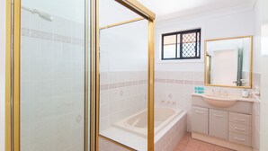A bathroom with a glass-enclosed shower, a bathtub, a sink, and a mirror. - Horizons 8 on the lake (forster)