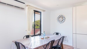 A dining area with a tiled table, chairs, a clock, and an air conditioning unit. - Horizons 8 on the lake (forster)