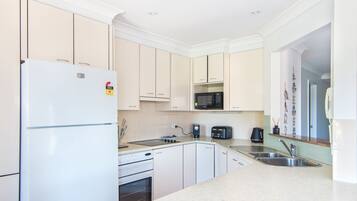 A modern kitchen with white cabinets, a refrigerator, a microwave, a coffee maker, and a toaster.