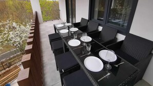 A balcony with a dining table set for four, black wicker chairs, and a view of trees and a road. - 3 BEDROOM APARTMENT VILLA MAREL (Cerdillo)