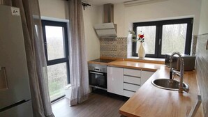 A modern kitchen with a built-in oven, a stainless steel sink, and a window with curtains. - 3 BEDROOM APARTMENT VILLA MAREL (Cerdillo)