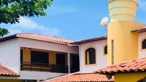 A building with a yellow facade and red-tiled roof, featuring large windows and a satellite dish. - Pousada Uba-Rio Porto de Galinhas (Ipojuca)