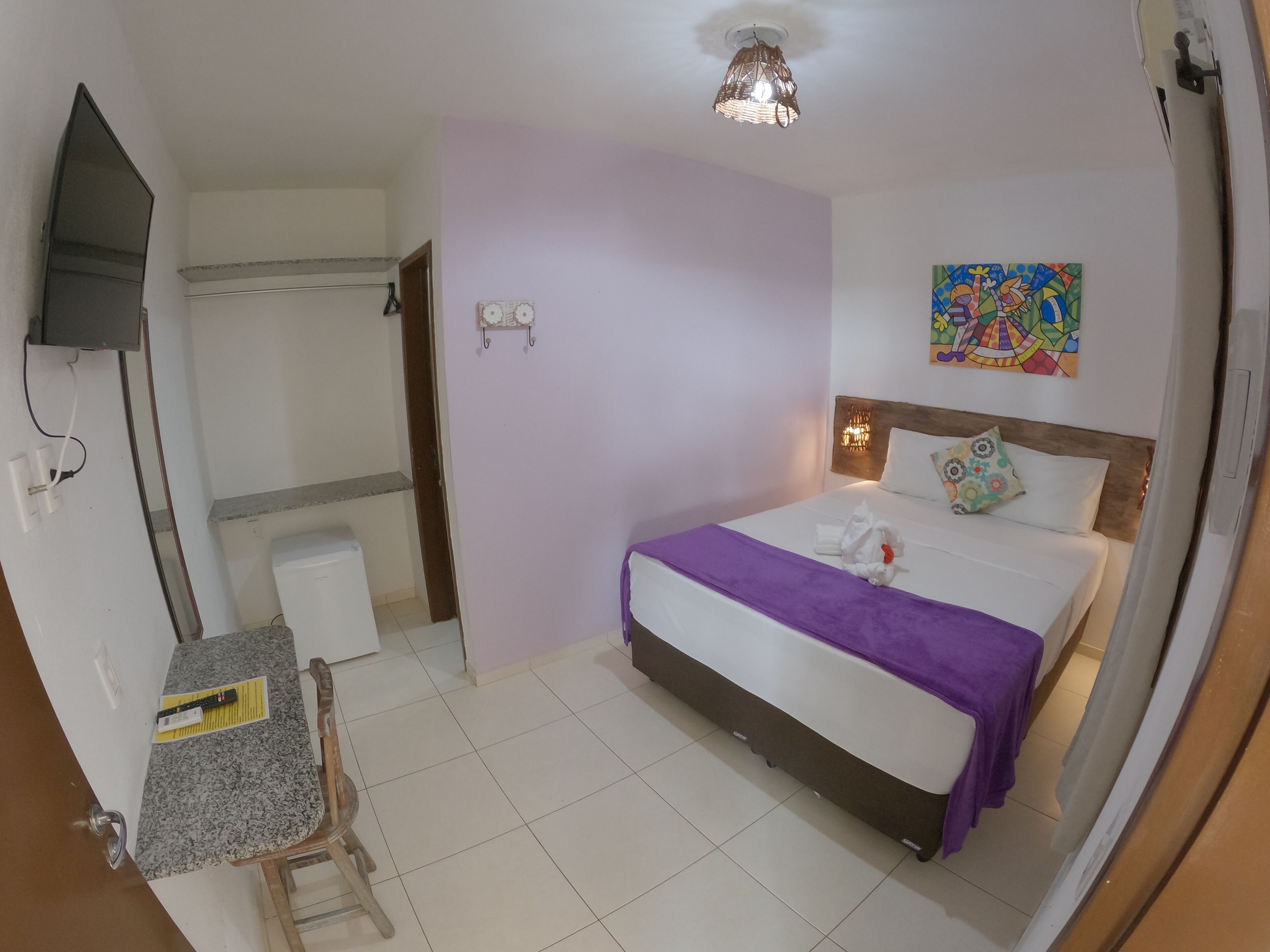 A hotel room with a bed, a desk, a chair, a television, and a bathroom.