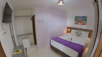 A hotel room with a bed, a desk, a chair, a television, and a bathroom.