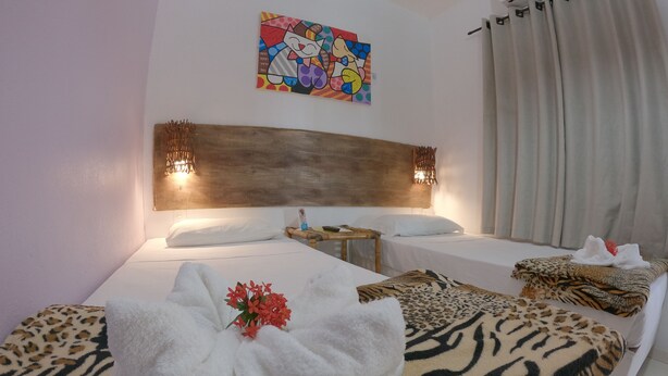 A hotel room with two beds, a headboard, a painting, and a window with curtains. - Pousada Uba-Rio Porto de Galinhas (Ipojuca)