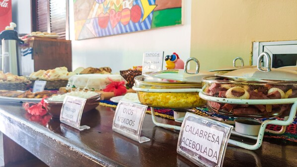 A buffet with various dishes labeled in Spanish, including 'Calabresa Acebolada'. - Pousada Uba-Rio Porto de Galinhas (Ipojuca)