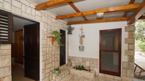 Ein überdachter Patio-Bereich mit Steinmauern, Holzbalken und einer Tür, die zu einem Raum führt.