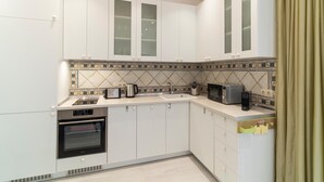 Een moderne keuken met witte kastjes, een ingebouwde oven, een magnetron en een waterkoker.
