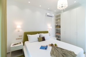 Quarto com cama, abajures, um candelabro, um ar condicionado e um guarda-roupa.