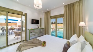 Een hotelkamer met een bed, een televisie, een bureau en uitzicht op een buitenzwembad.