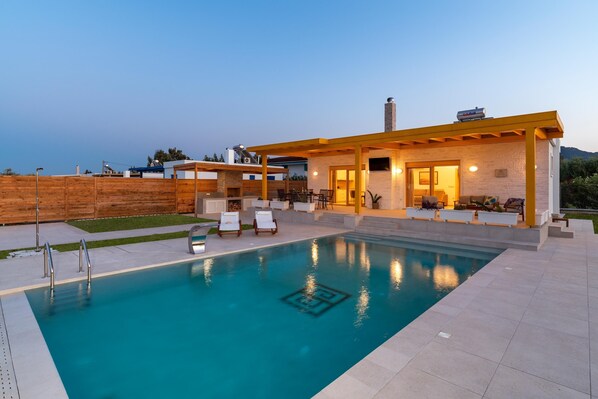 Una casa moderna con piscina, mobiliario de exterior y vistas al paisaje.