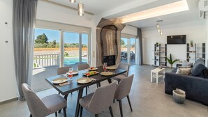 Un salon moderne comprenant un coin repas, une cheminée et un téléviseur.