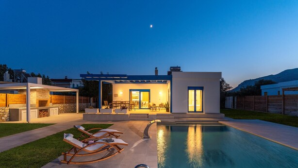 Ein modernes Haus mit Swimmingpool, Sitzgelegenheiten im Freien und einer Terrassenfläche.
