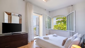 A modern bedroom with a bed, a TV, and a balcony with curtains.