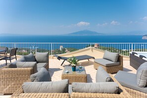 Una terraza con mobiliario de mimbre y vistas al mar y a la montaña.