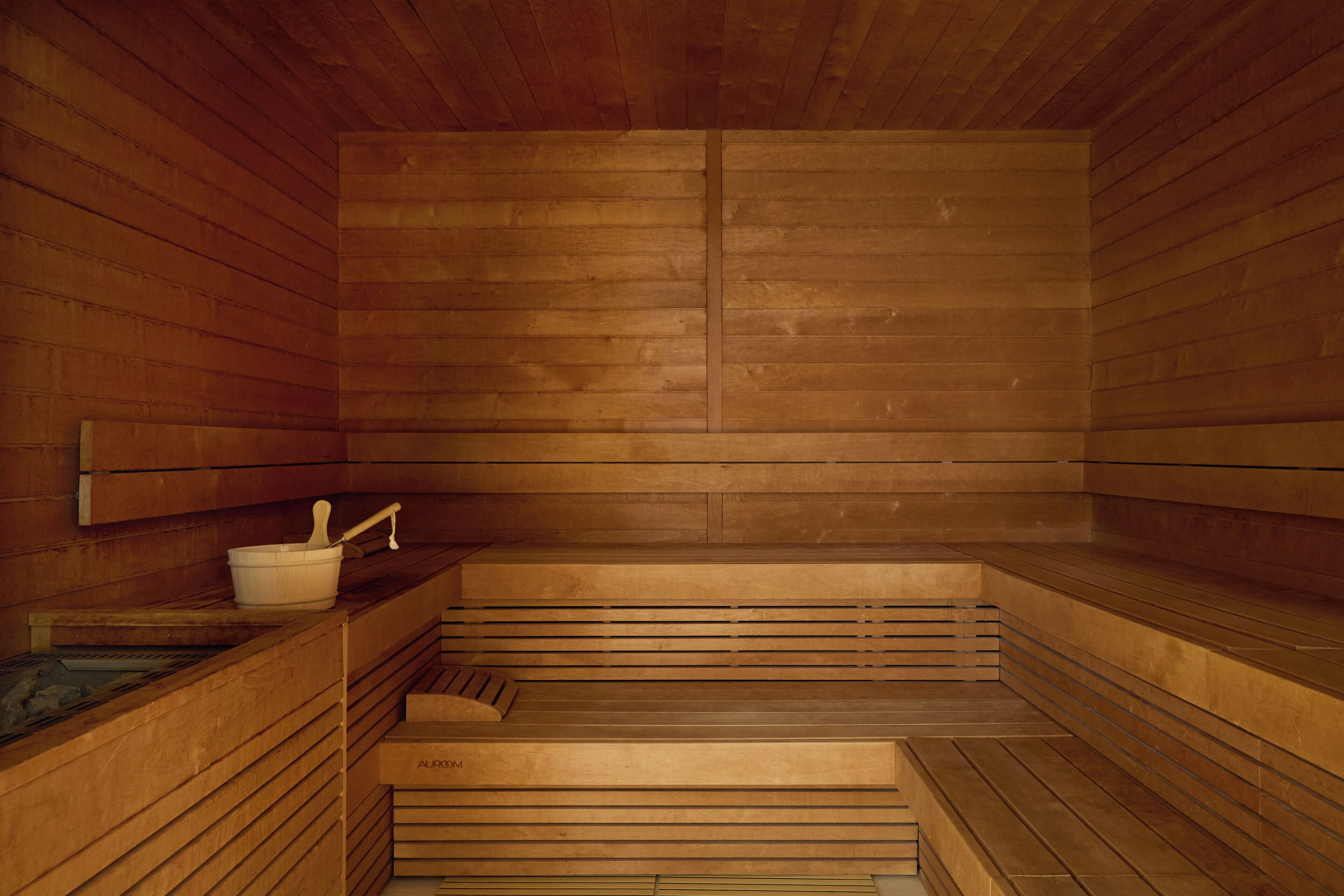 A sauna with wooden benches and a small basin with a ladle.