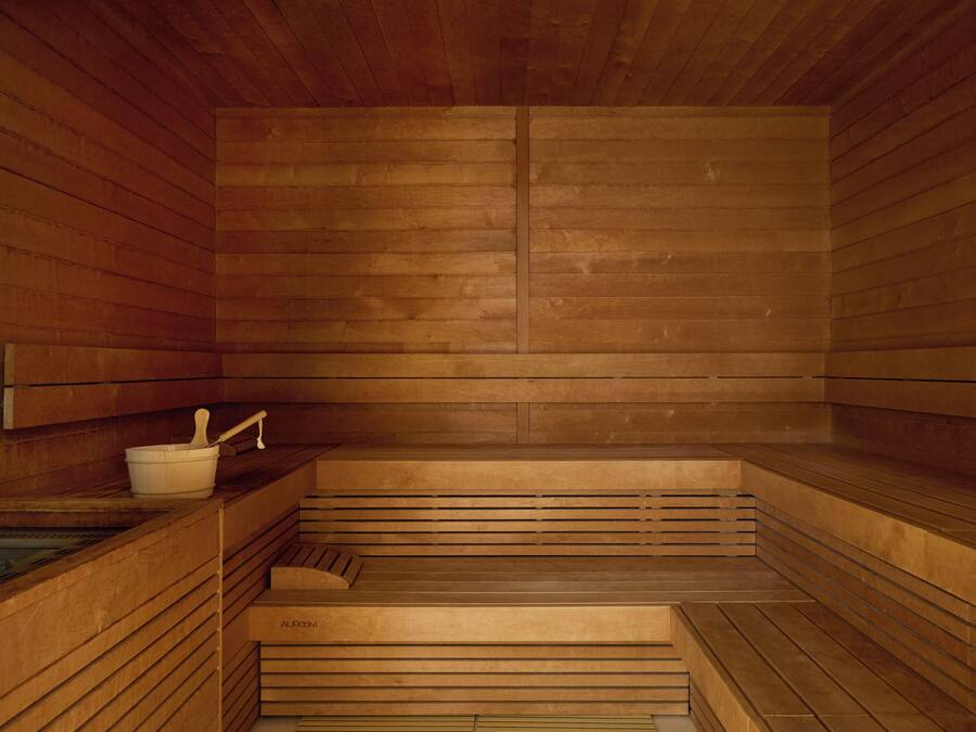 A sauna with wooden benches and a small basin with a ladle.