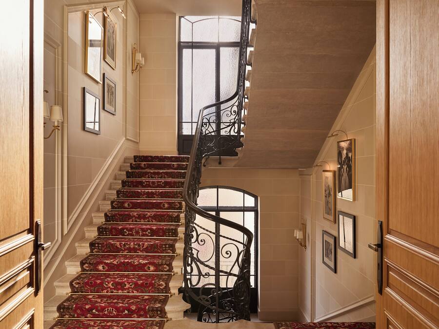 Una amplia escalera con barandillas decoradas y peldaños alfombrados en rojo que conducen a una plataforma.
