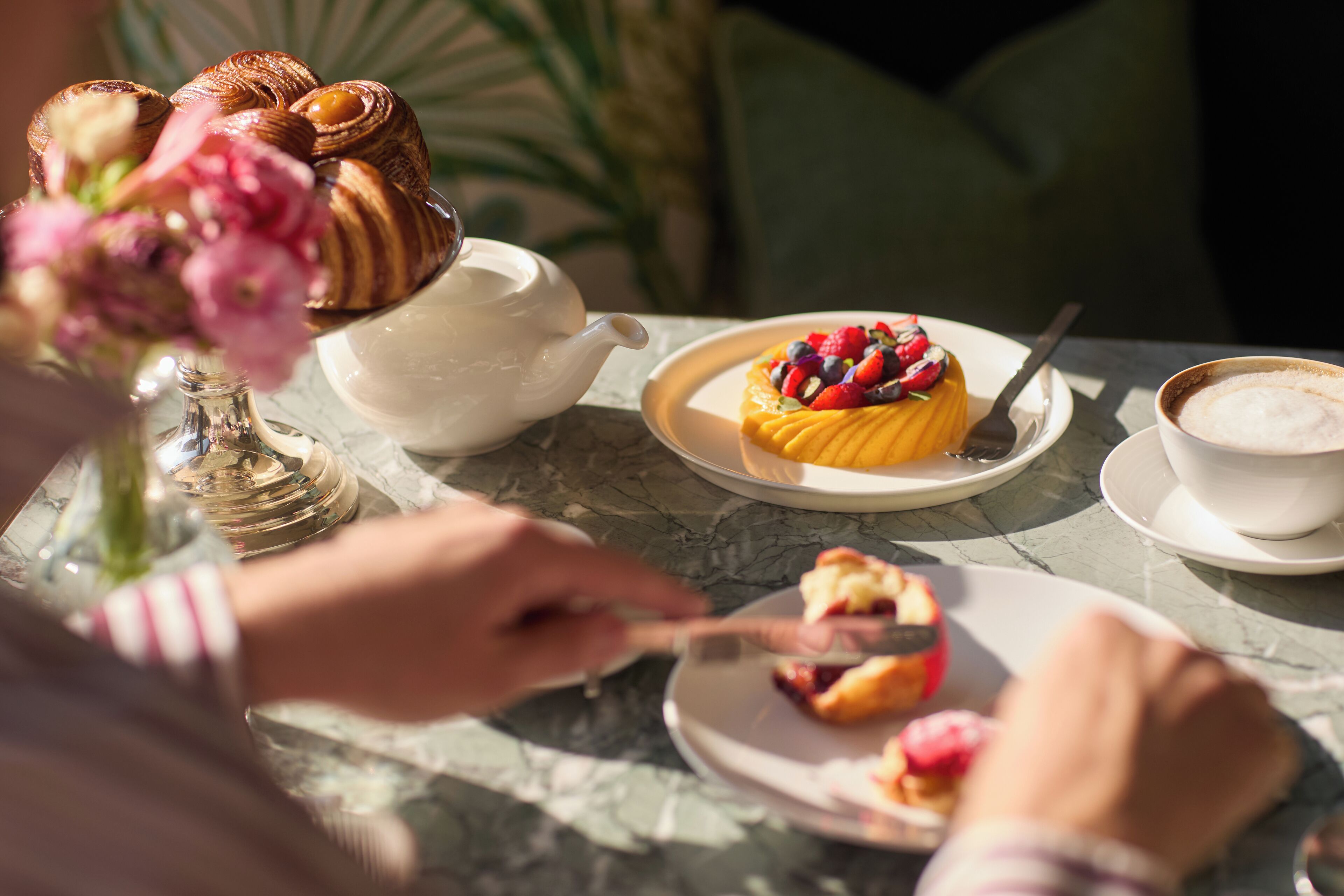 Una mesa con un pastel, una tetera y una taza de café.