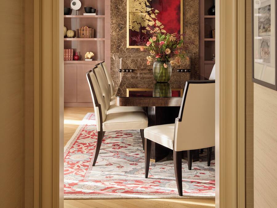 A dining area with a marble wall, a red abstract painting, and a vase with flowers.