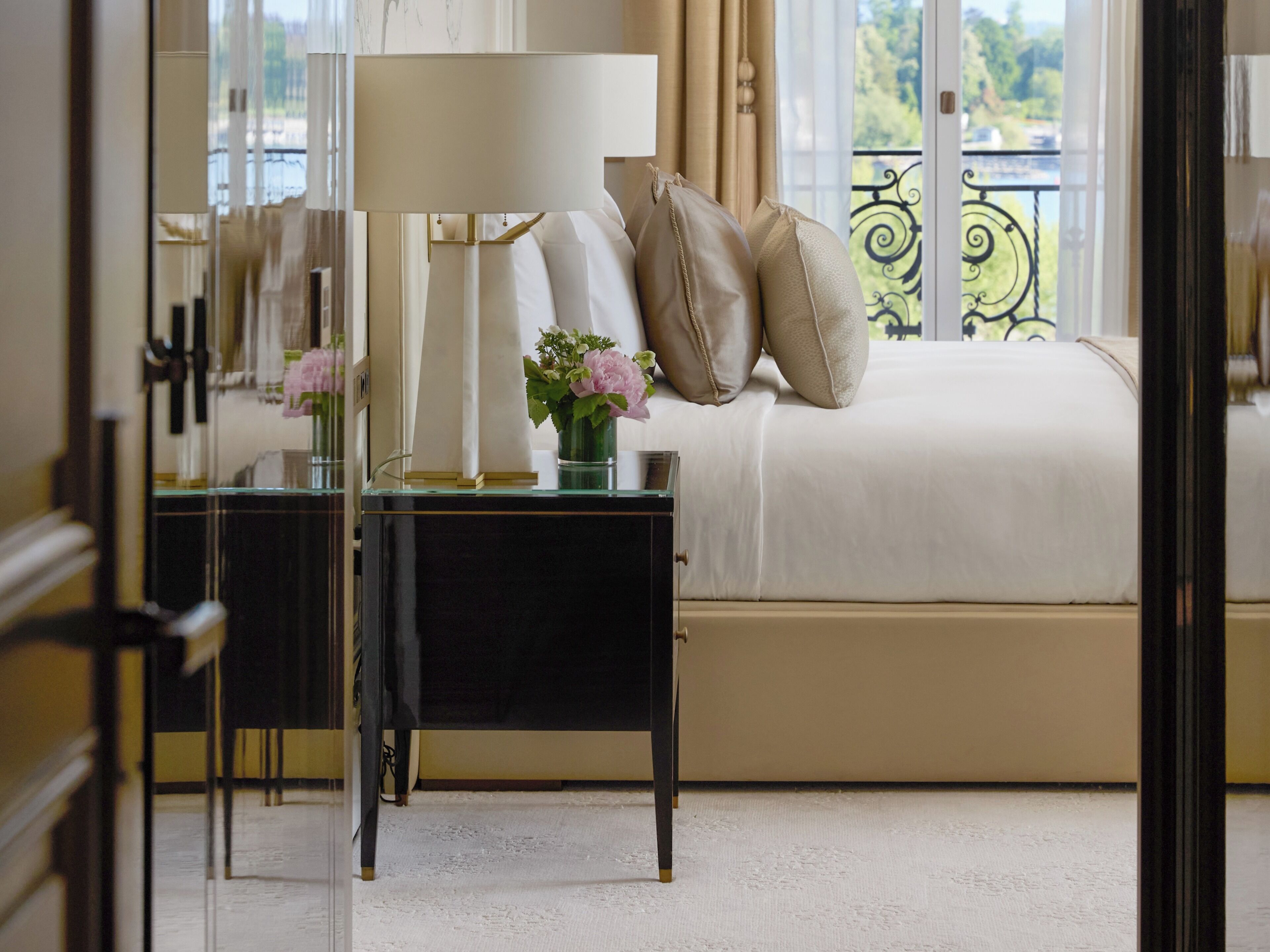 A neatly arranged bedroom with a bed, bedside tables, a lamp, and a vase with flowers.