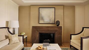 A living room with a fireplace, a sofa, a coffee table with a fruit bowl, and a side table with a lamp.