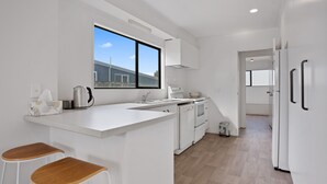 A modern kitchen with white cabinetry, a large window, and a built-in island with stools.