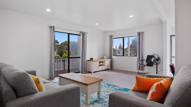 A modern living room with grey sofas, a wooden coffee table, and a view of a balcony.