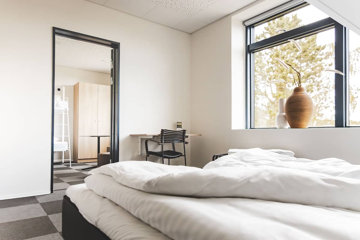 A modern bedroom with a large bed, a desk, and a chair.