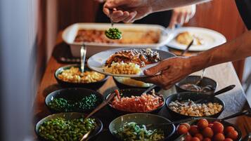 Una mesa de comedor con diferentes platos y una persona sirviendo comida.