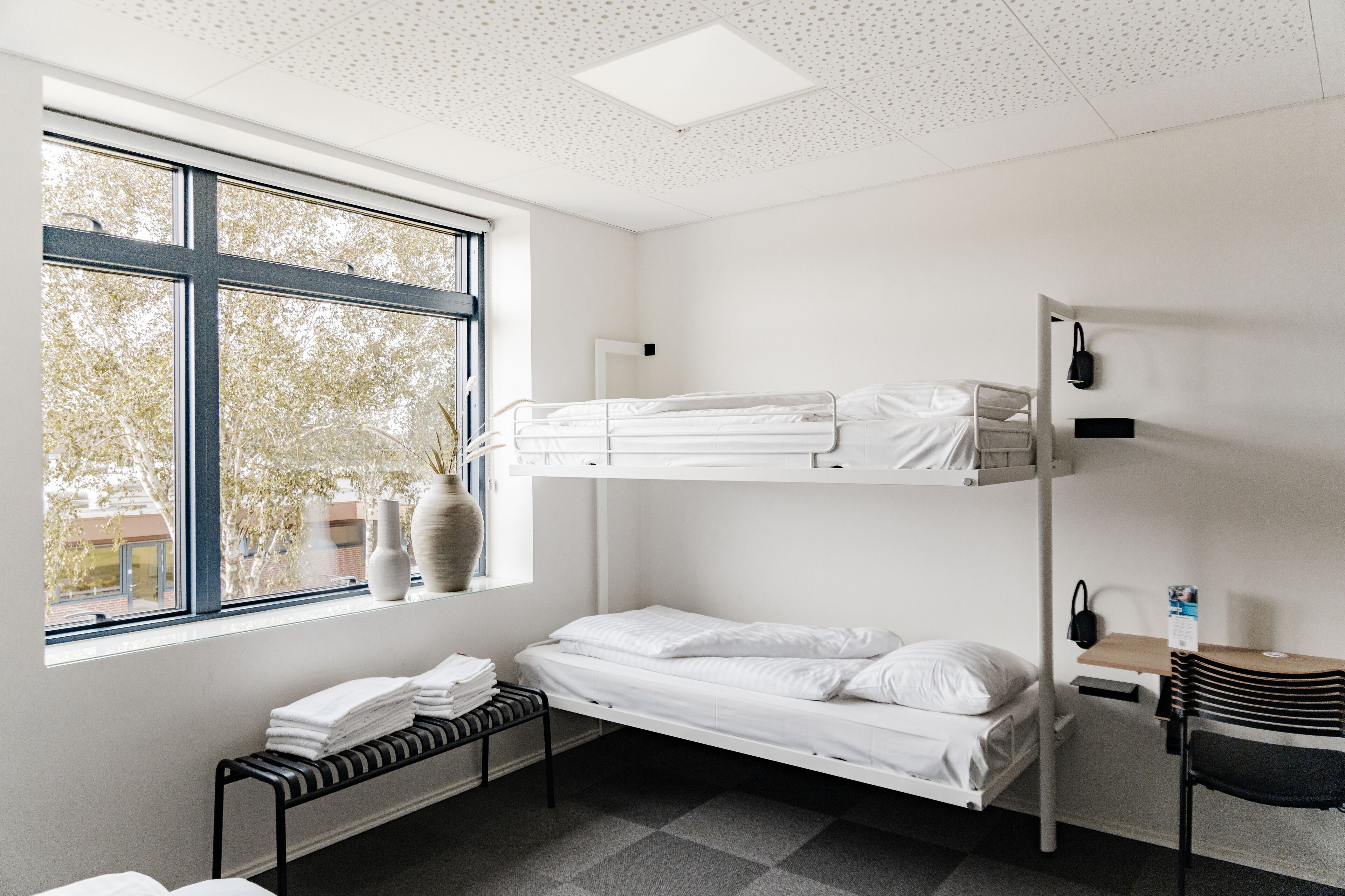 Habitación con literas, una ventana, un escritorio y una silla.