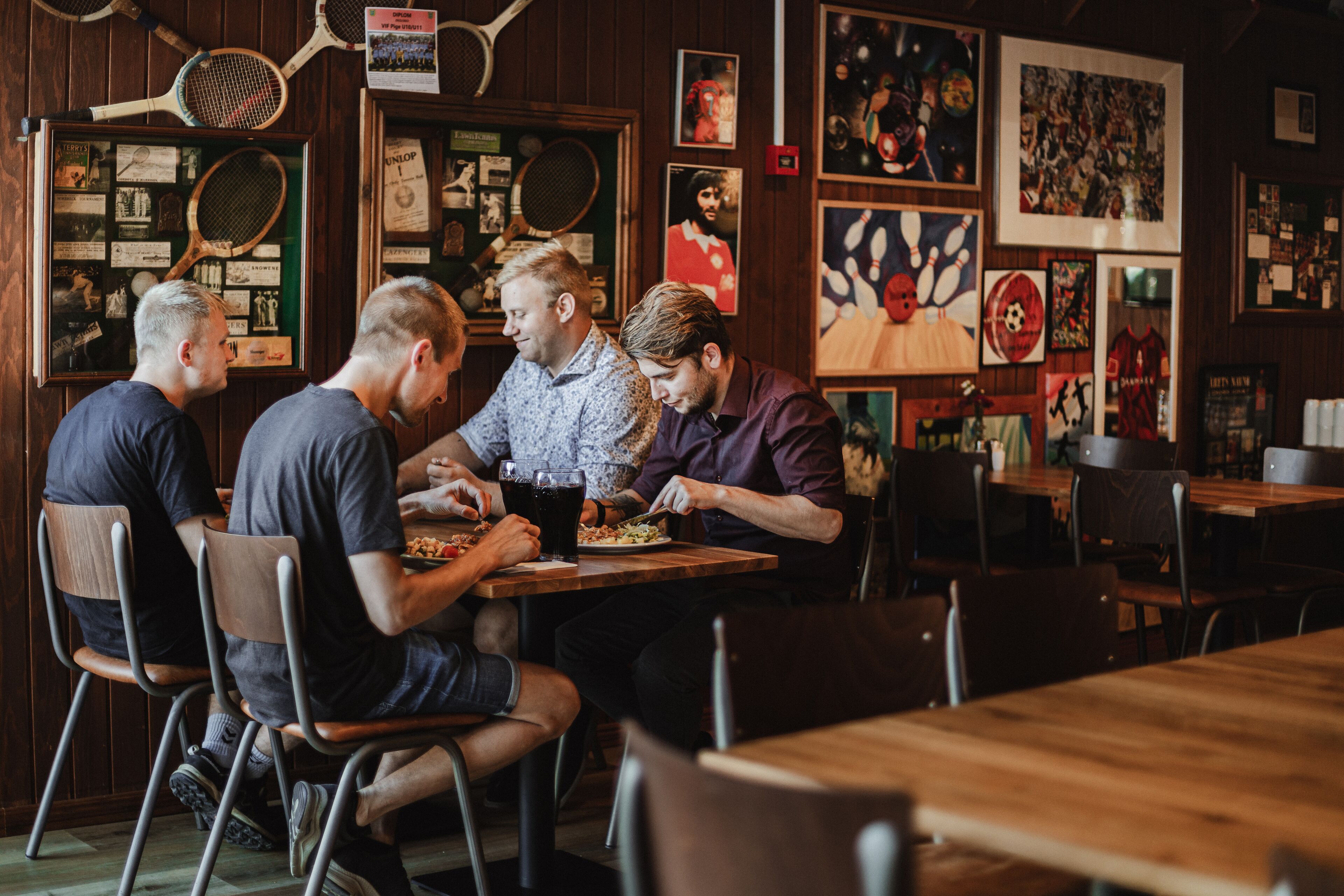 A group of people dining at a restaurant with wooden walls and various sports memorabilia displayed.