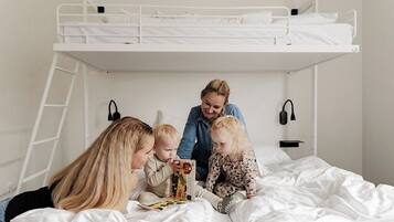 A bunk bed room with a ladder, a bedside table, and a wall-mounted lamp.