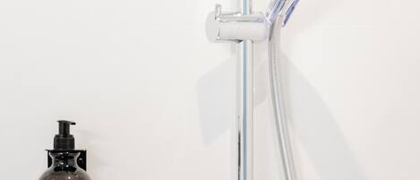 Una ducha moderna con cabezal de ducha manual y controles incorporados a la pared.